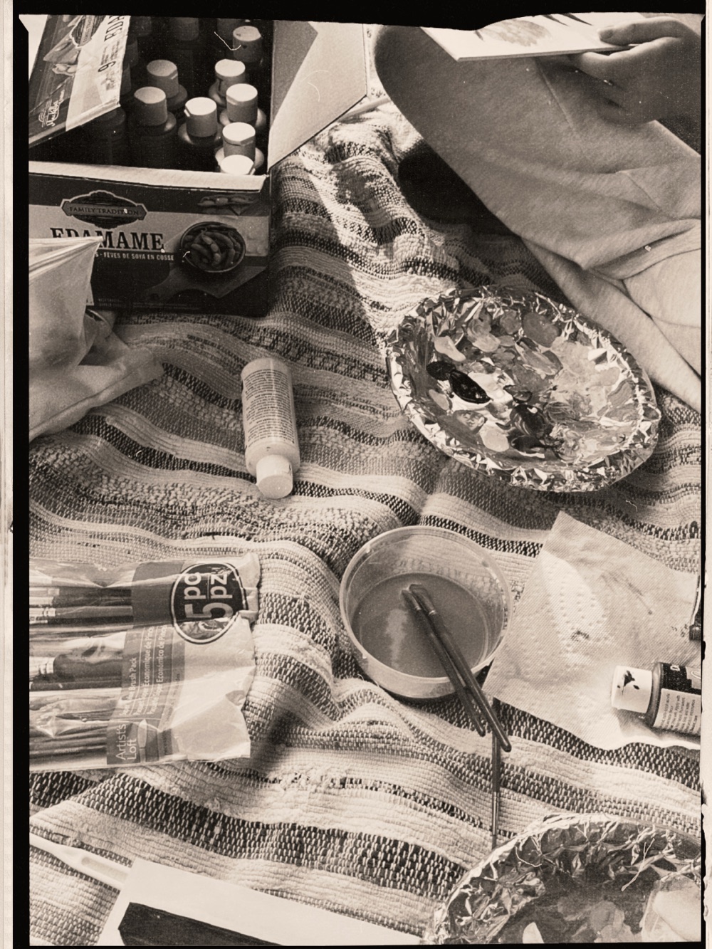 Paints and brushes spread on a striped blanket