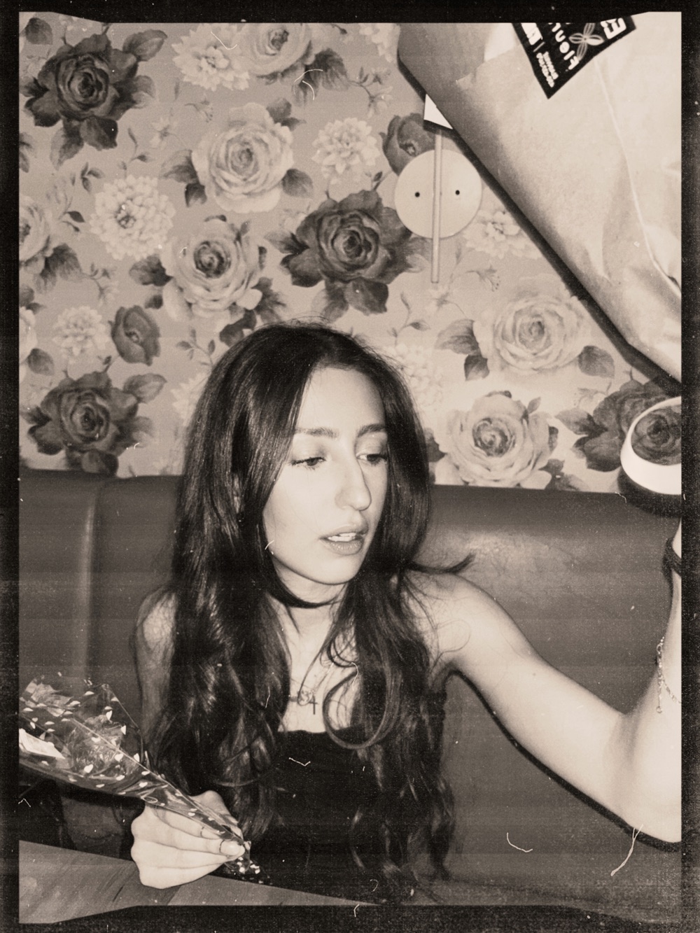 Eleni in a photo booth with floral wallpaper