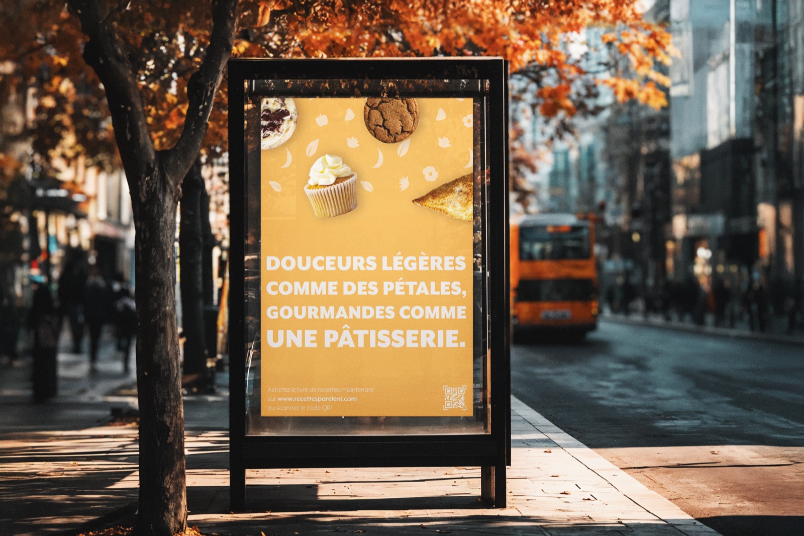Pétales et Pâtisseries cookbook poster in a bus shelter on an autumn street